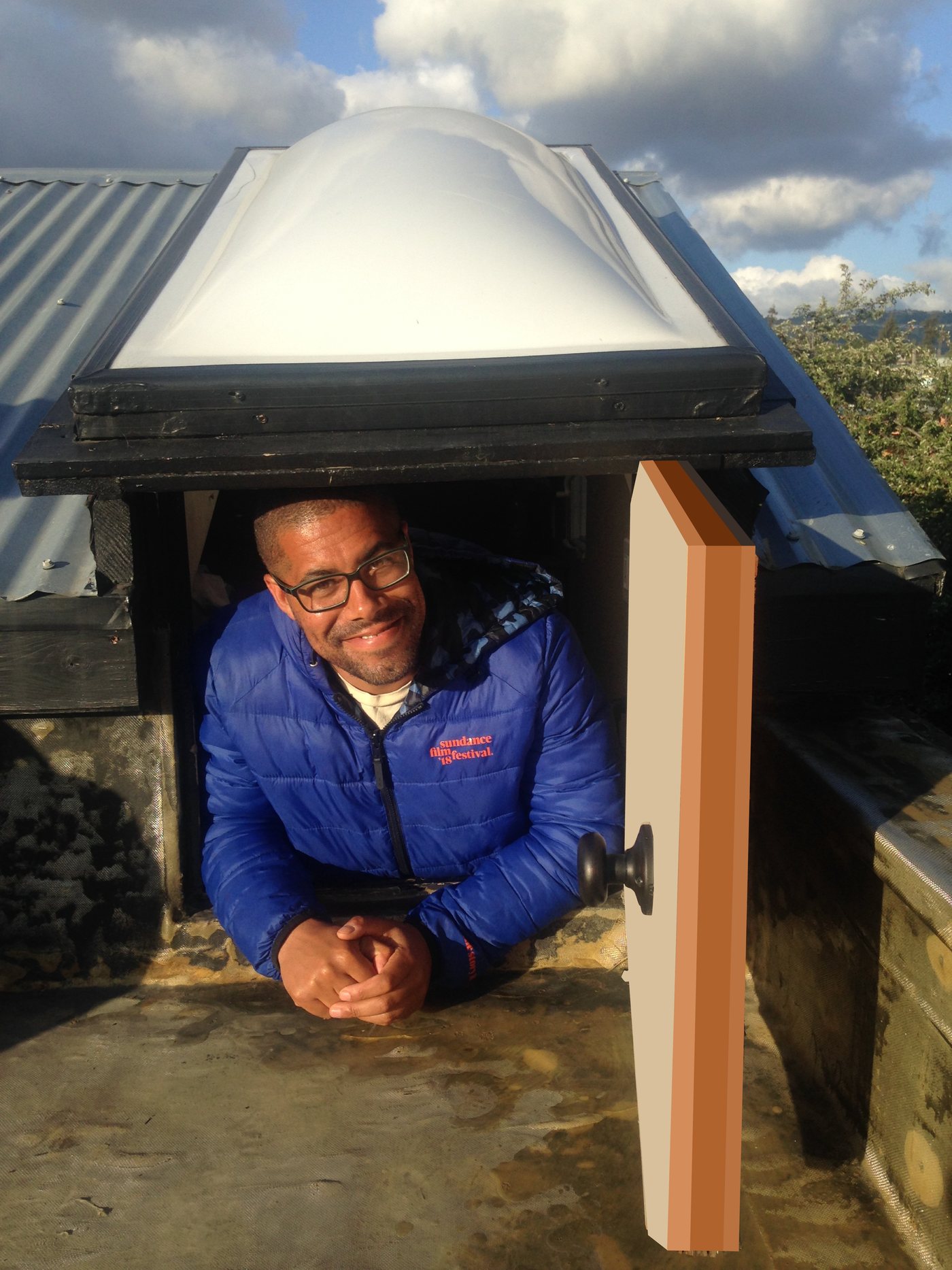 Adam Garrett-Clark leaning out of a rooftop hatch